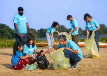 Team of young and diversity volunteer workers group enjoy charitable social work outdoor in cleaning up garbage and waste separation project at river beach